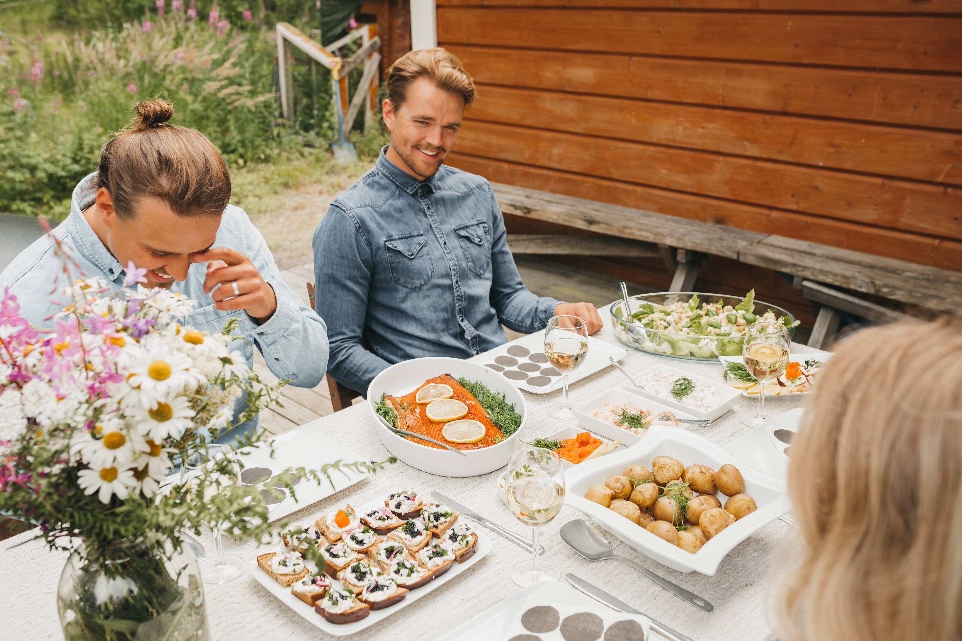 People sitting at a dinner table eating Finnish summer foods.
