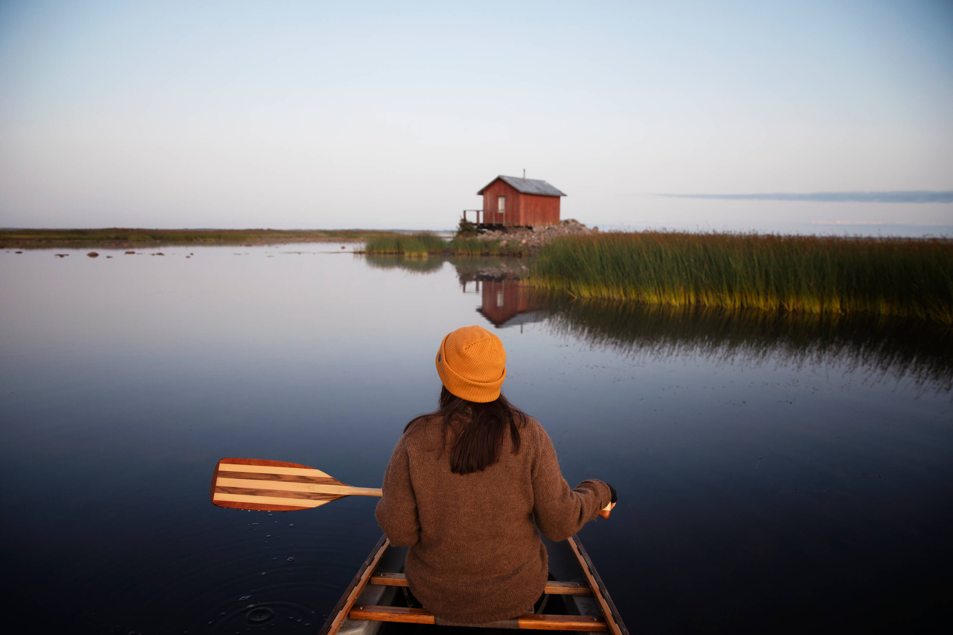 Eine Person paddelt im Sommer auf einem ruhigen See in Finnisch-Lappland.